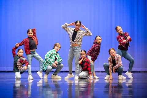 Group of young musical theater students on stage wearing street clothes costumes