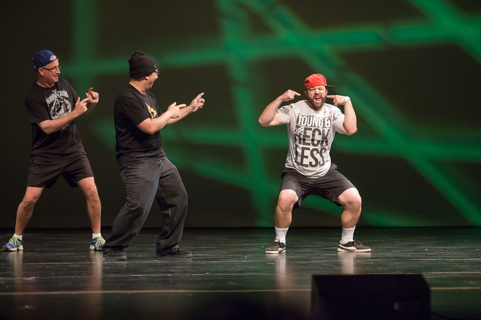 Three men on green stage doing improv