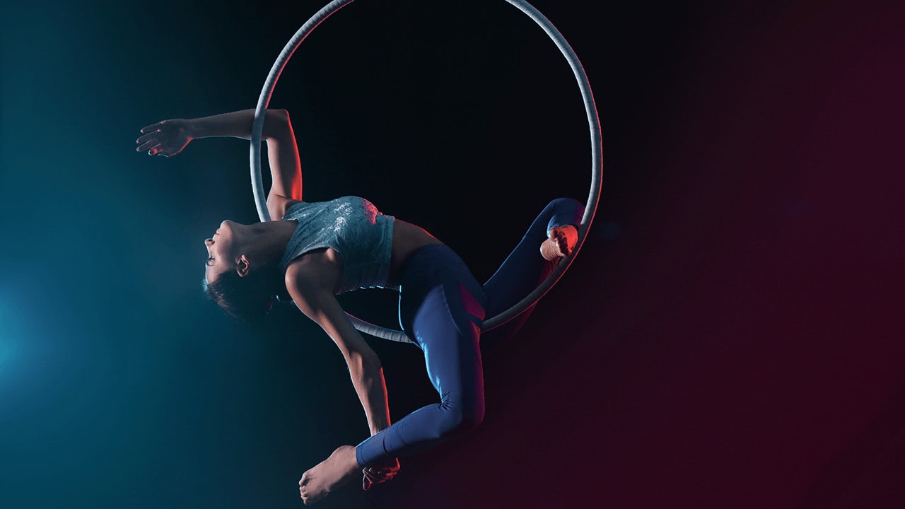 Woman performing aerial hoop dancing on stage hanging from hoop in air