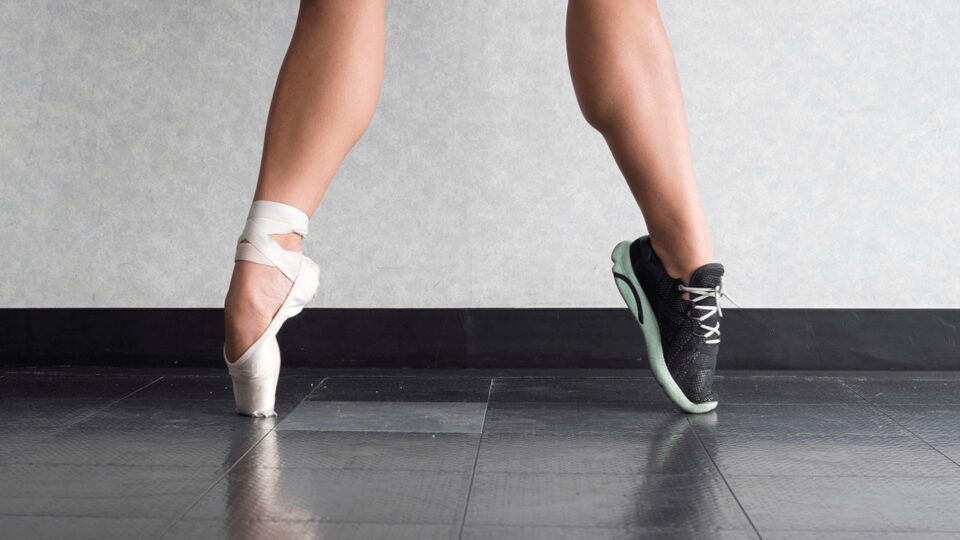 Ballet dancer's legs with pointe shoes on one foot and sneakers